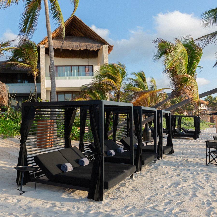 Vista de la playa de TAGO Tulum con un espacio cómodo para sentarse o recostarse y disfrutar del mar Caribe.