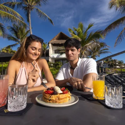 Pareja disfrutando de un desayuno en la playa frente al mar en TAGO Tulum