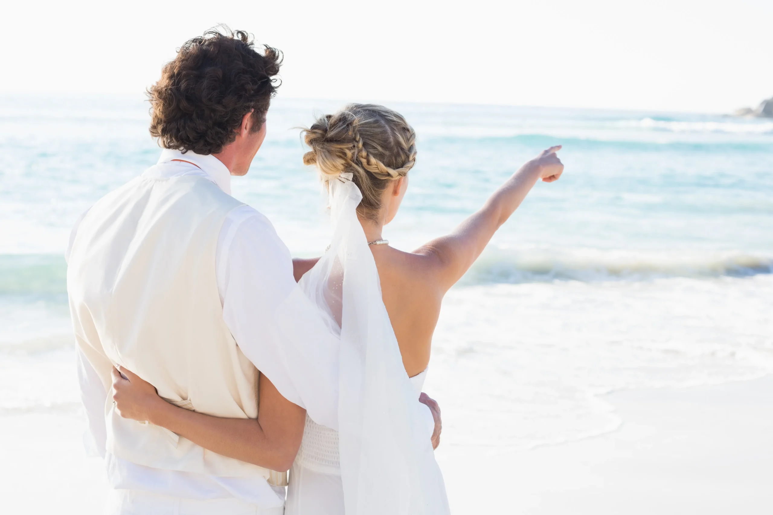 recien-casados-de-pie-junto-al-mar-con-la-esposa-senalando_11zon