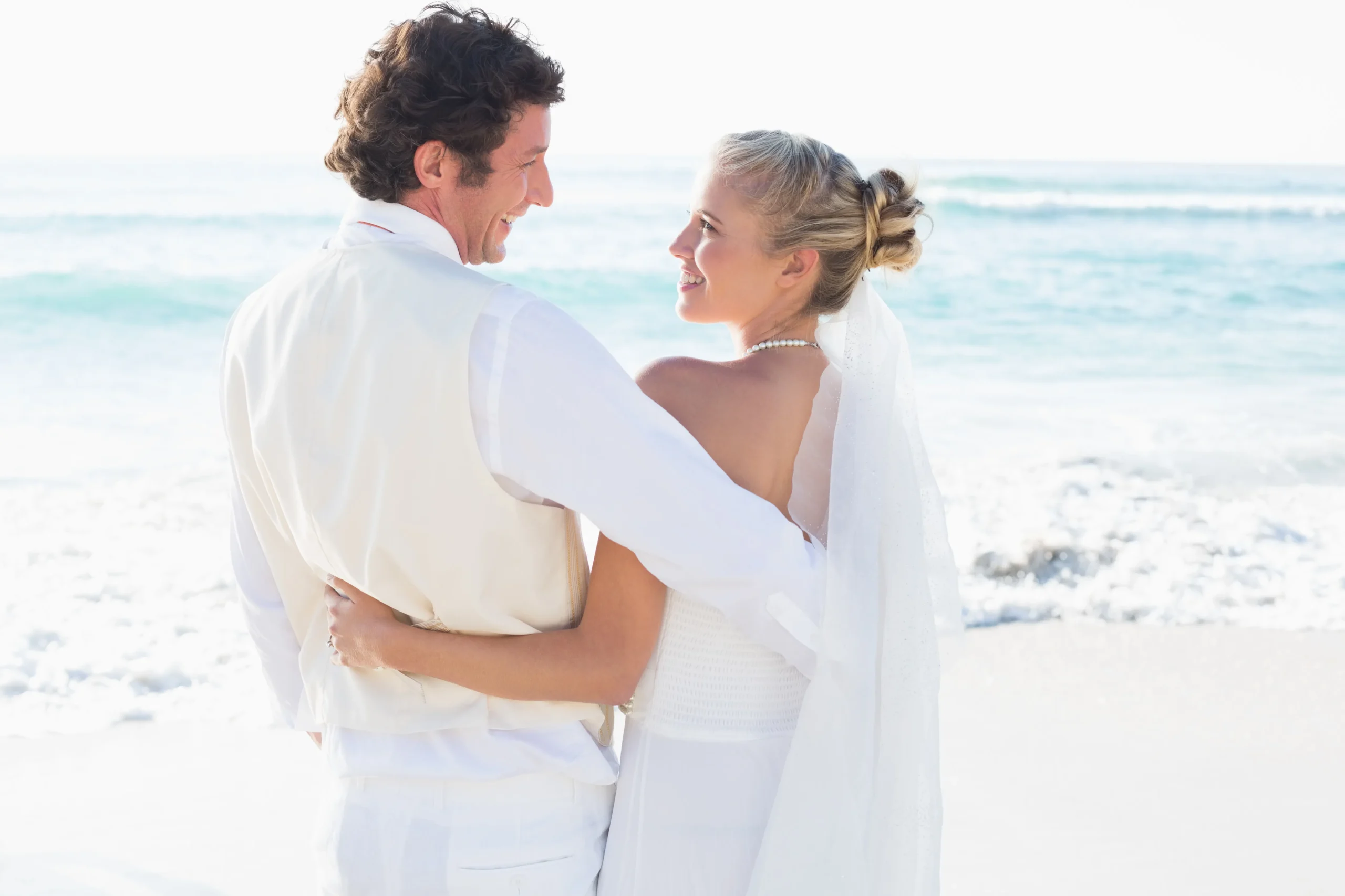 recien-casados-de-pie-junto-al-mar-sonriendo-el-uno-al-otro_11zon