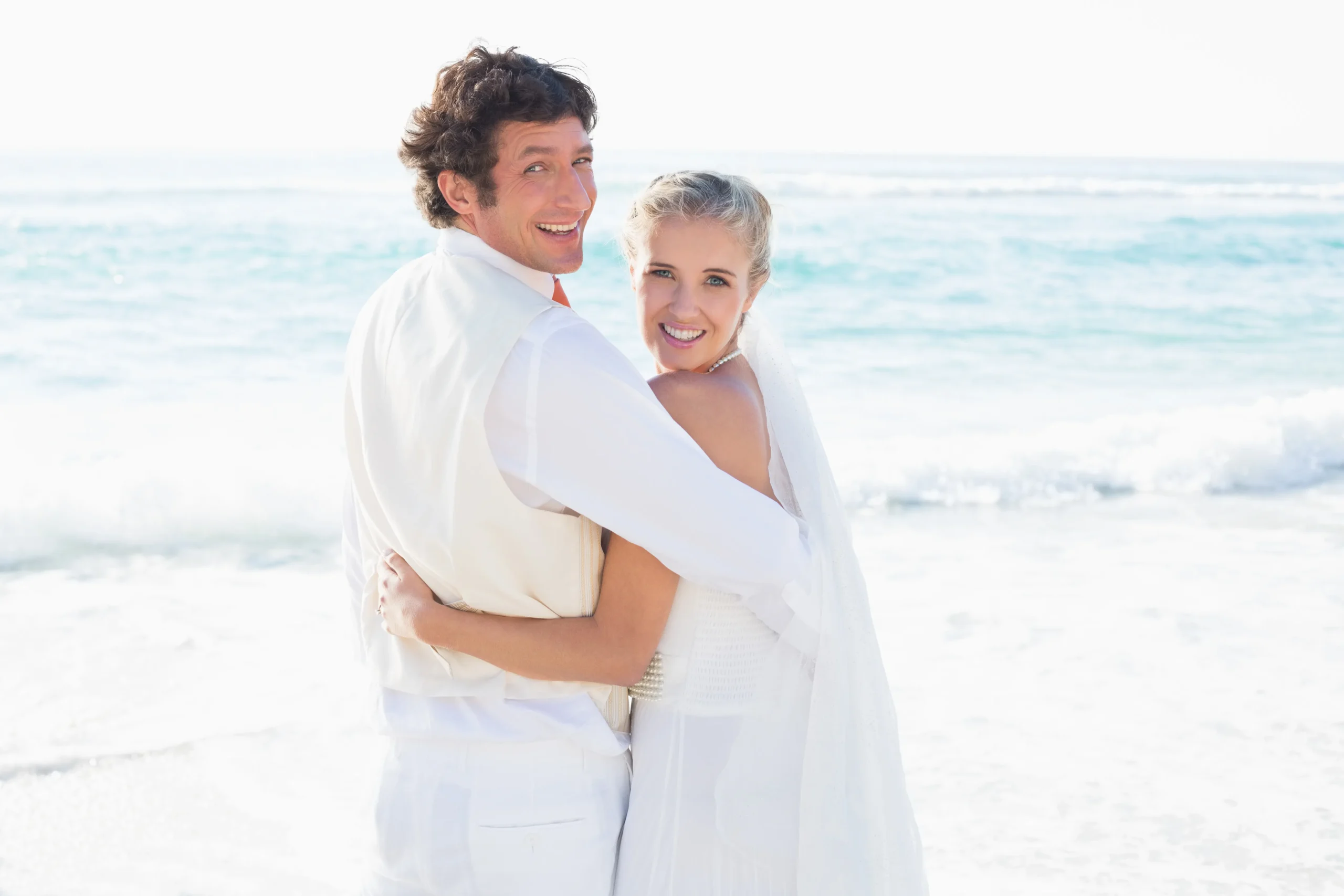 recien-casados-de-pie-junto-al-mar-sonriendo-la-camara_11zon